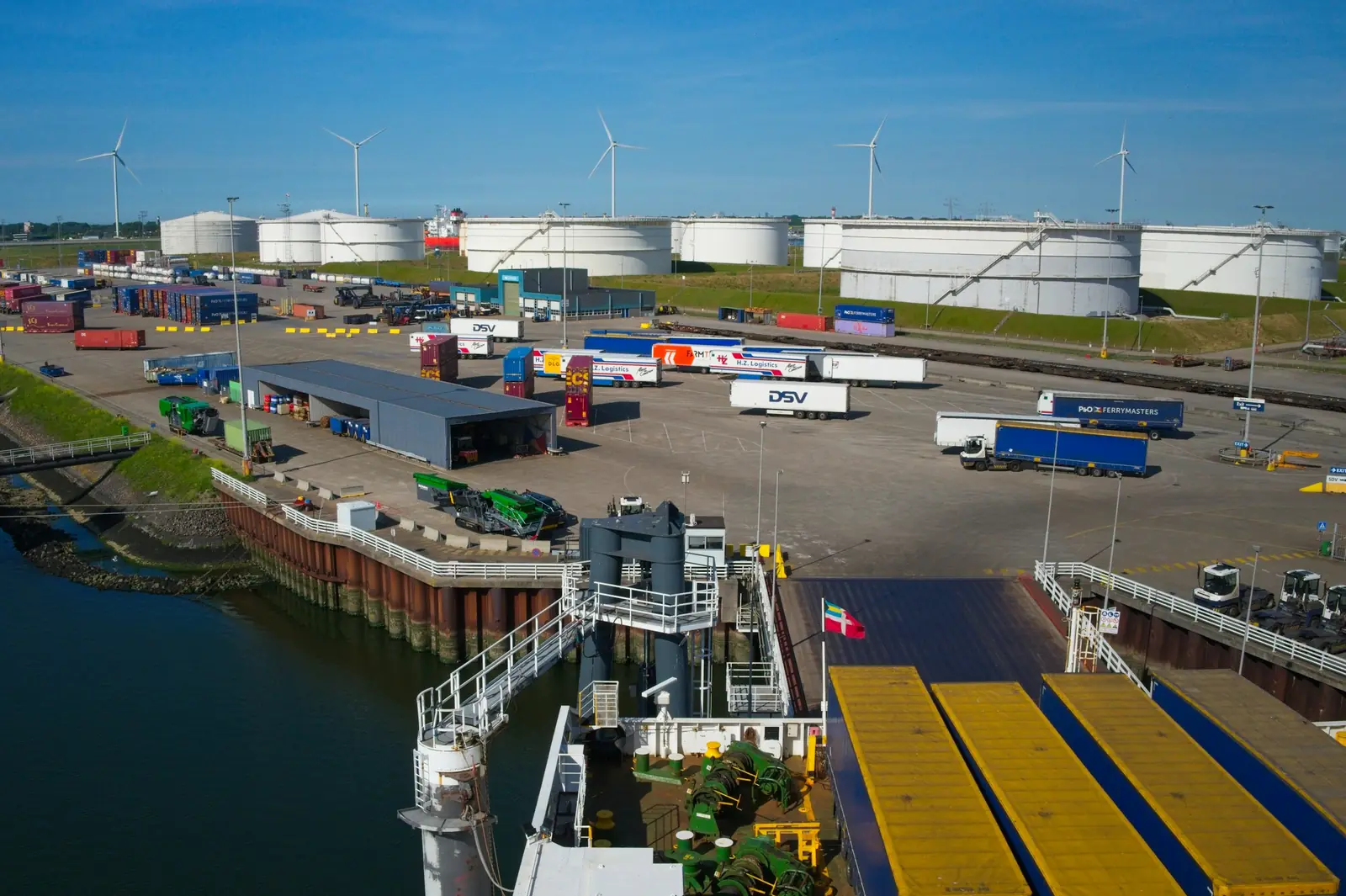 Industrial port with storage tanks, trucks and a vessel berth